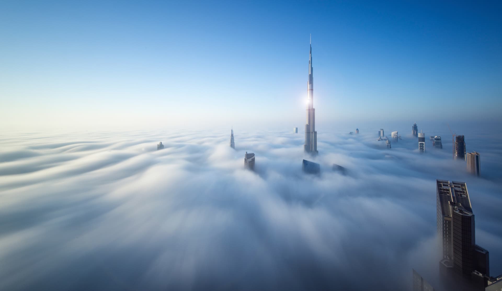 The Burj Khalifa and Dubai skyline rising above the clouds